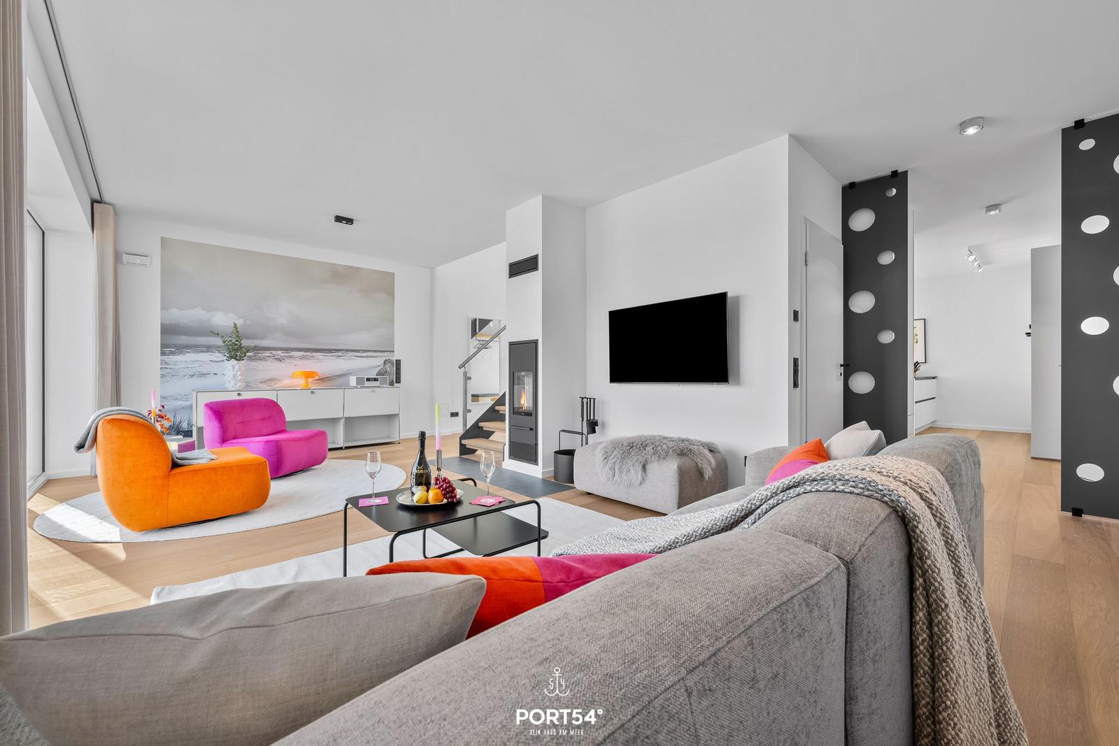 Wohnzimmer mit Sofa, Sitzgelegenheiten und Fernseher.