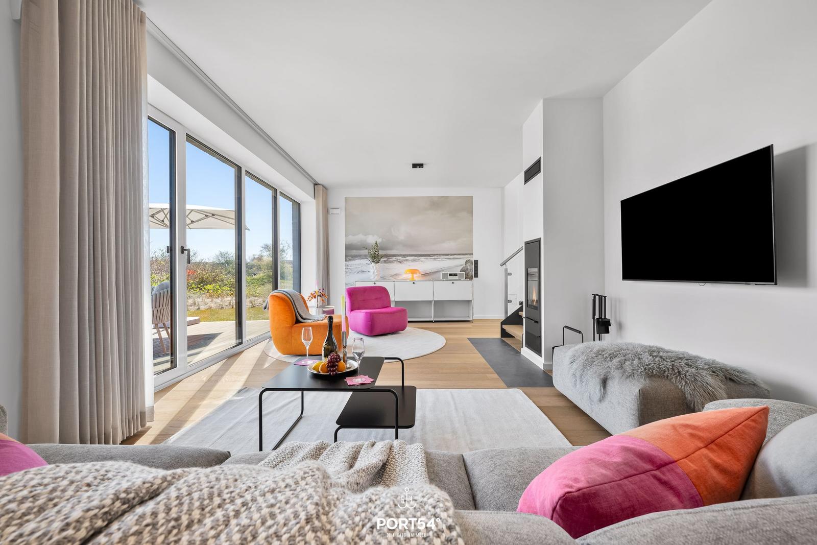 Wohnzimmer mit großem Fenster, Sofa, Fernseher und Kamin.
