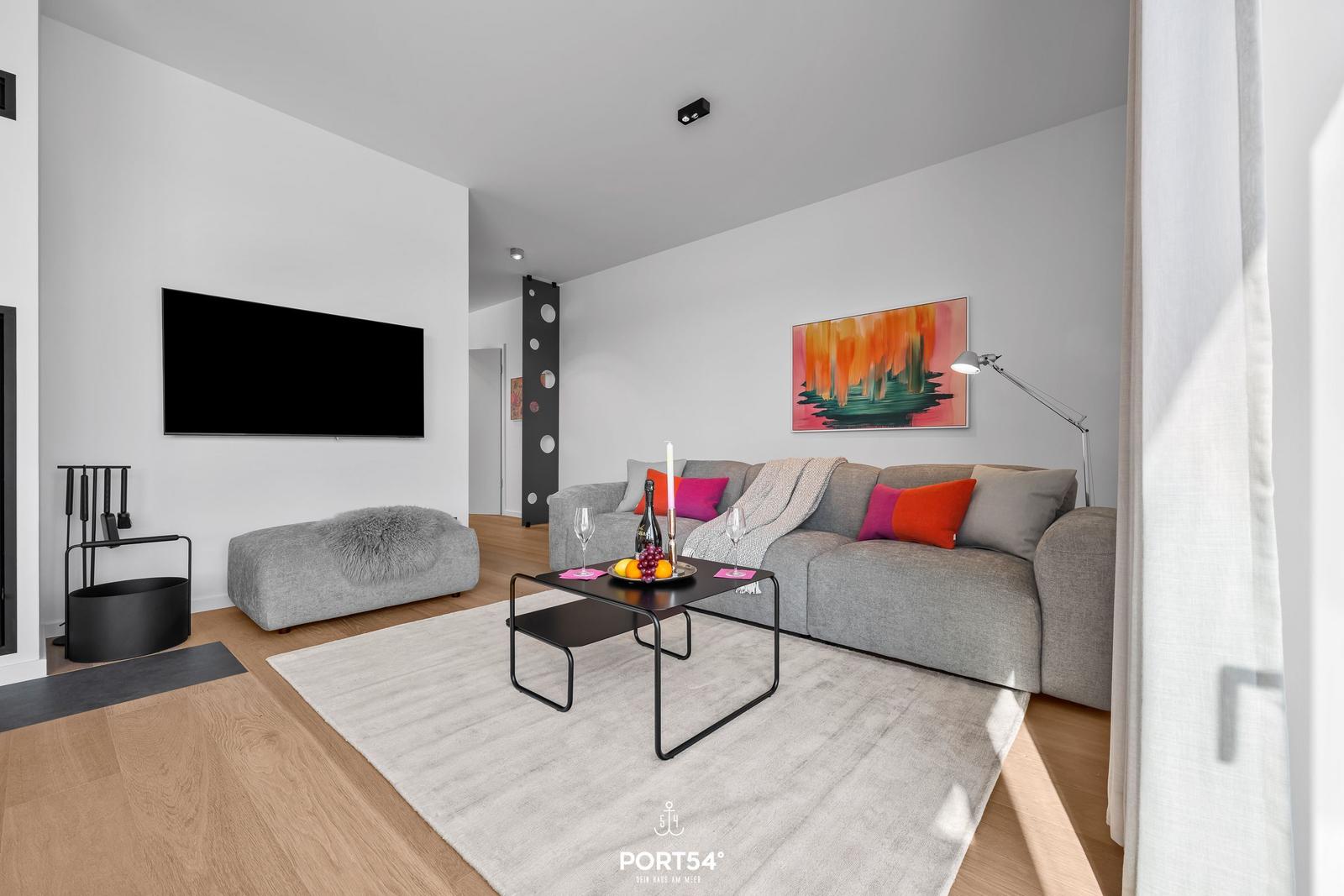 Wohnzimmer mit Sofa, Couchtisch und Fernseher an der Wand.