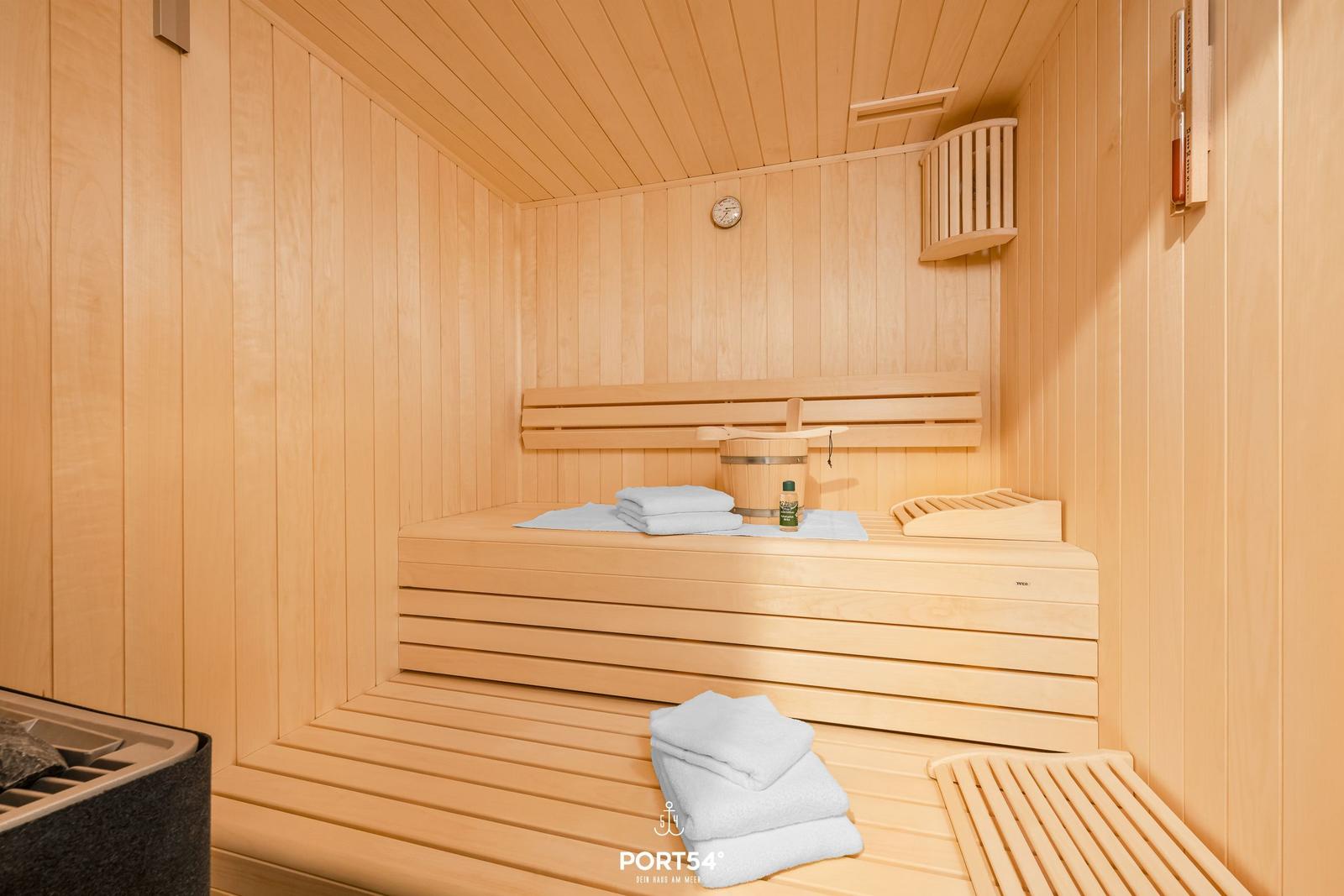 Sauna mit Holzbank, Handtuch und Thermometer an der Wand.