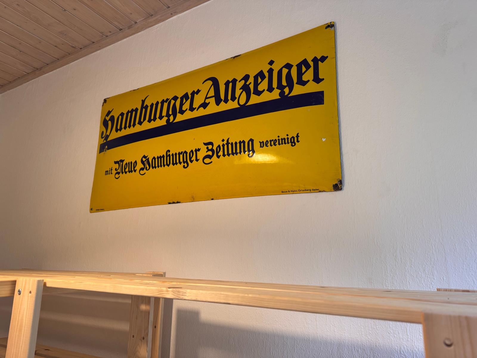 Gelbes Schild mit Schriftzug an Wand über Holzbank