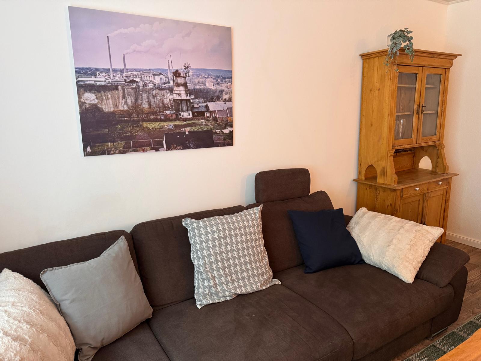 Ein braunes Sofa mit Kissen steht vor einer Wand mit einem großen Bild.