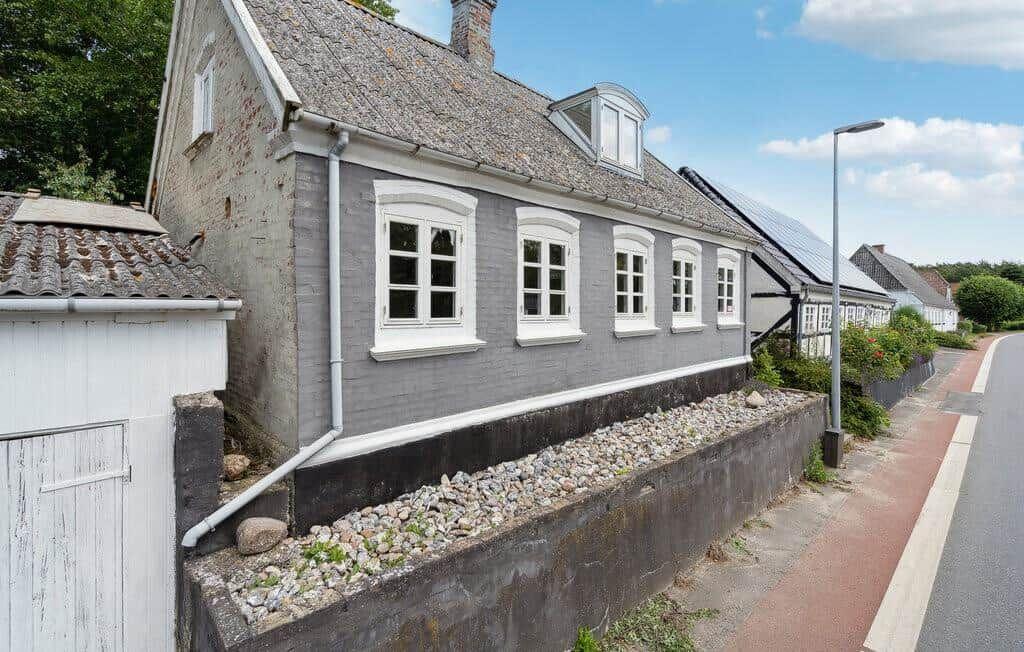 A gray house with white windows and a slate roof along a street.