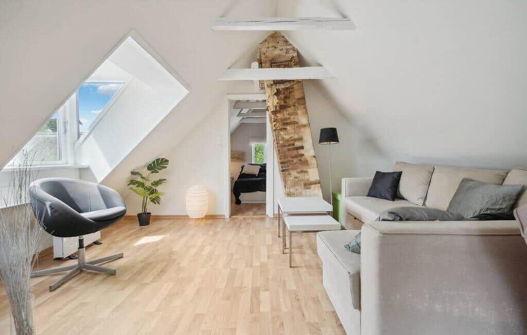 Living area with sofa, chair, and wooden floor under sloped ceilings.
