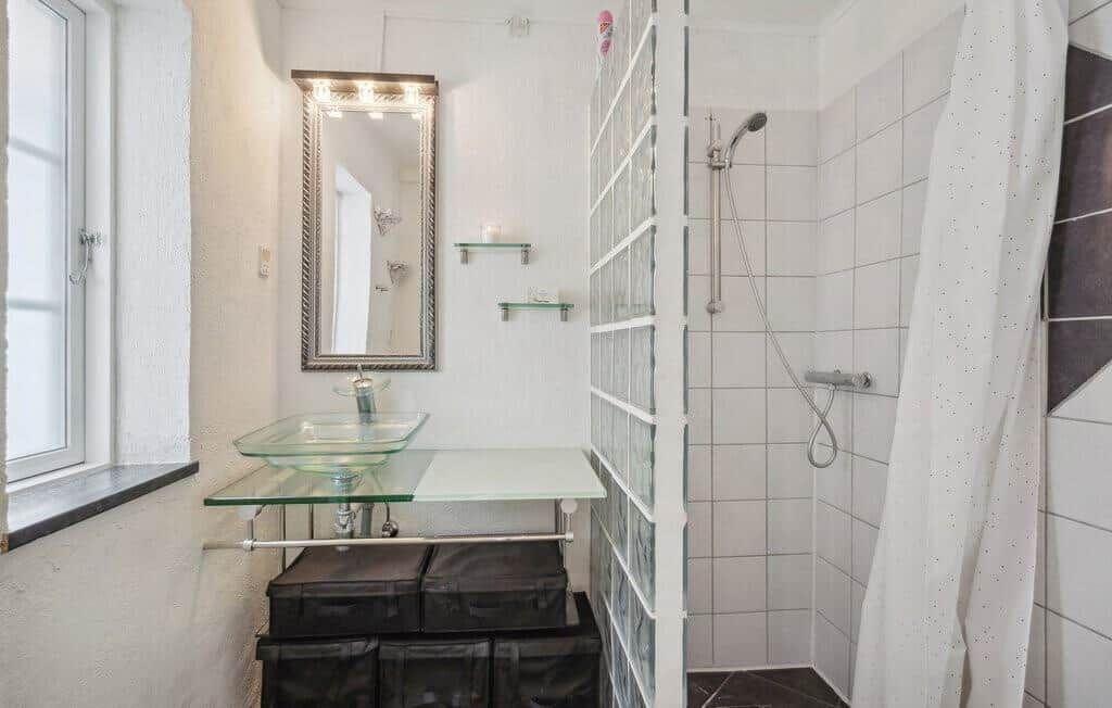 Bathroom with shower, mirror, and glass sink.