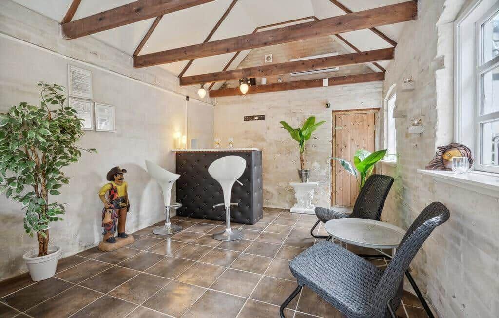 Room with wooden beams, bar stools, plants, and seating by window