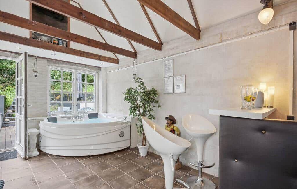 Living space with hot tub, wooden beams, plant, and bar stools.