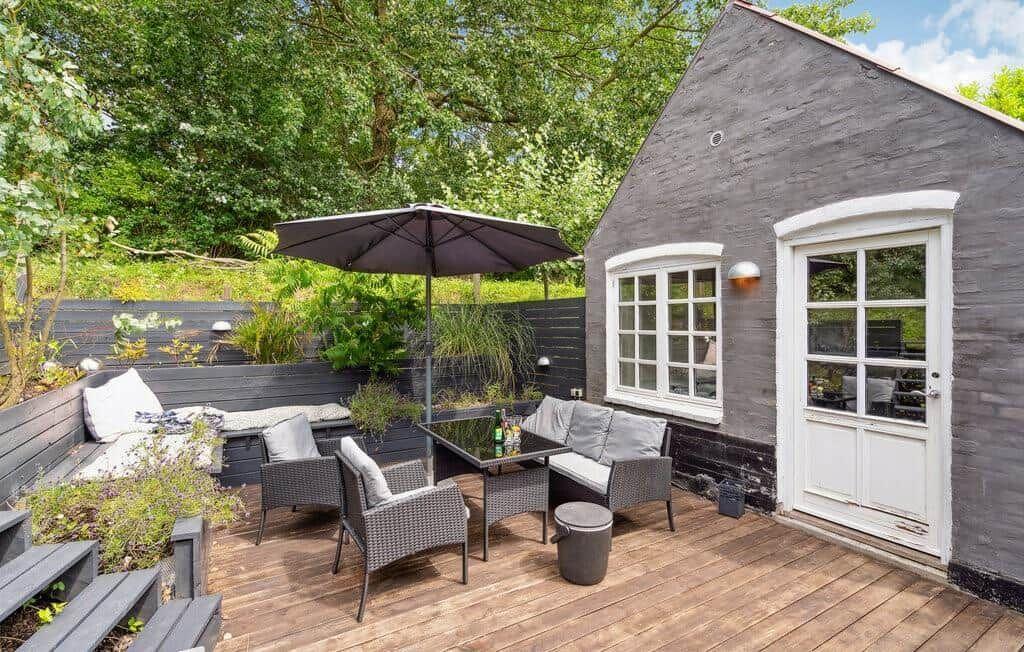 Terrace with seating, umbrella, and plants. Black facade and white windows.