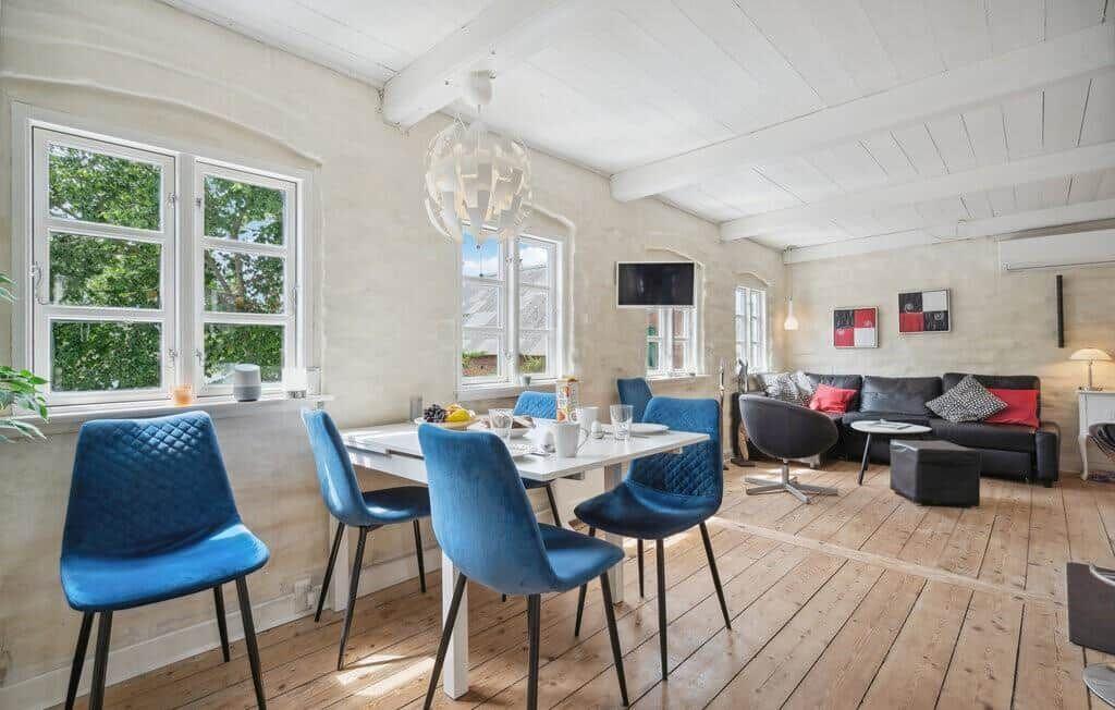 Dining area with blue chairs and living room with sofa and TV.