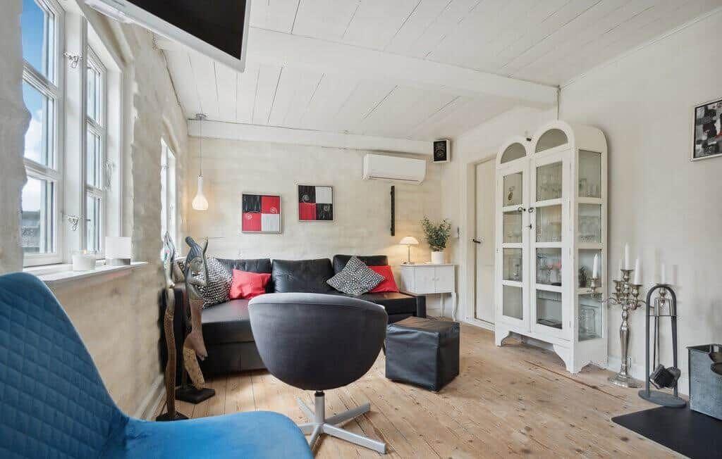 Living room with sofa, seating and glass cabinet. Wooden floor and large windows.