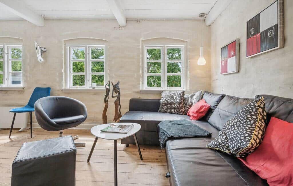 Living room with sofa, seating, and windows overlooking greenery.