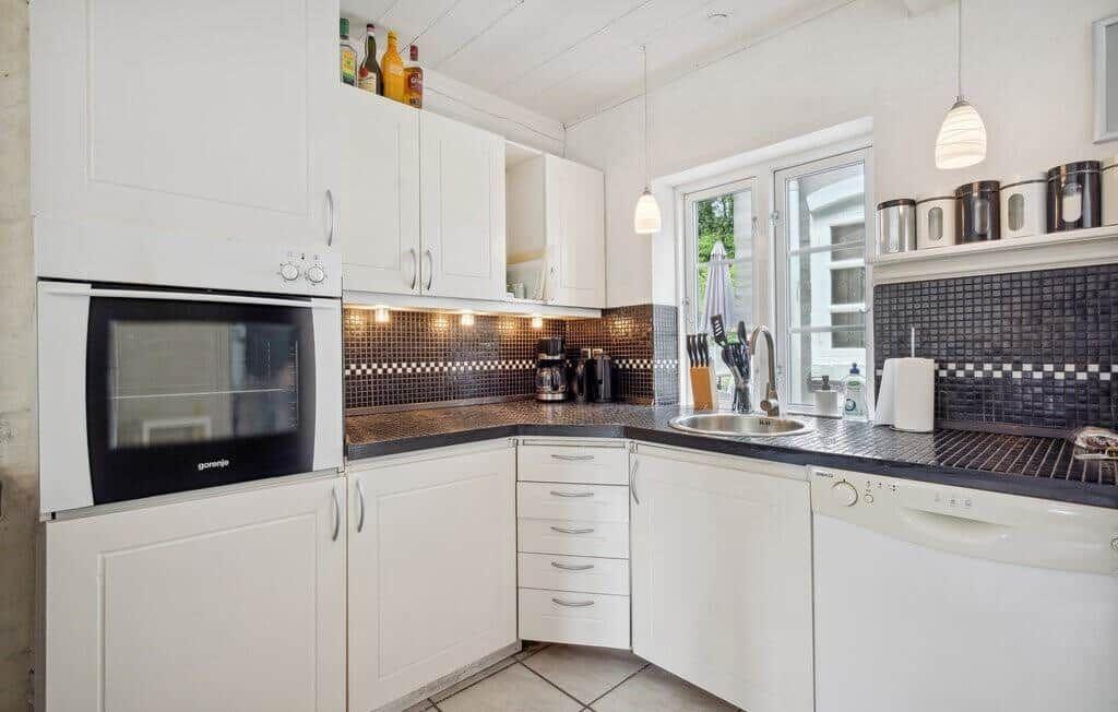 Kitchen with white cabinets, dark countertop, and window with view outside.