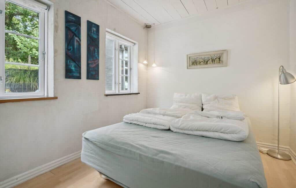 Bedroom with bed, windows, and wall decor.