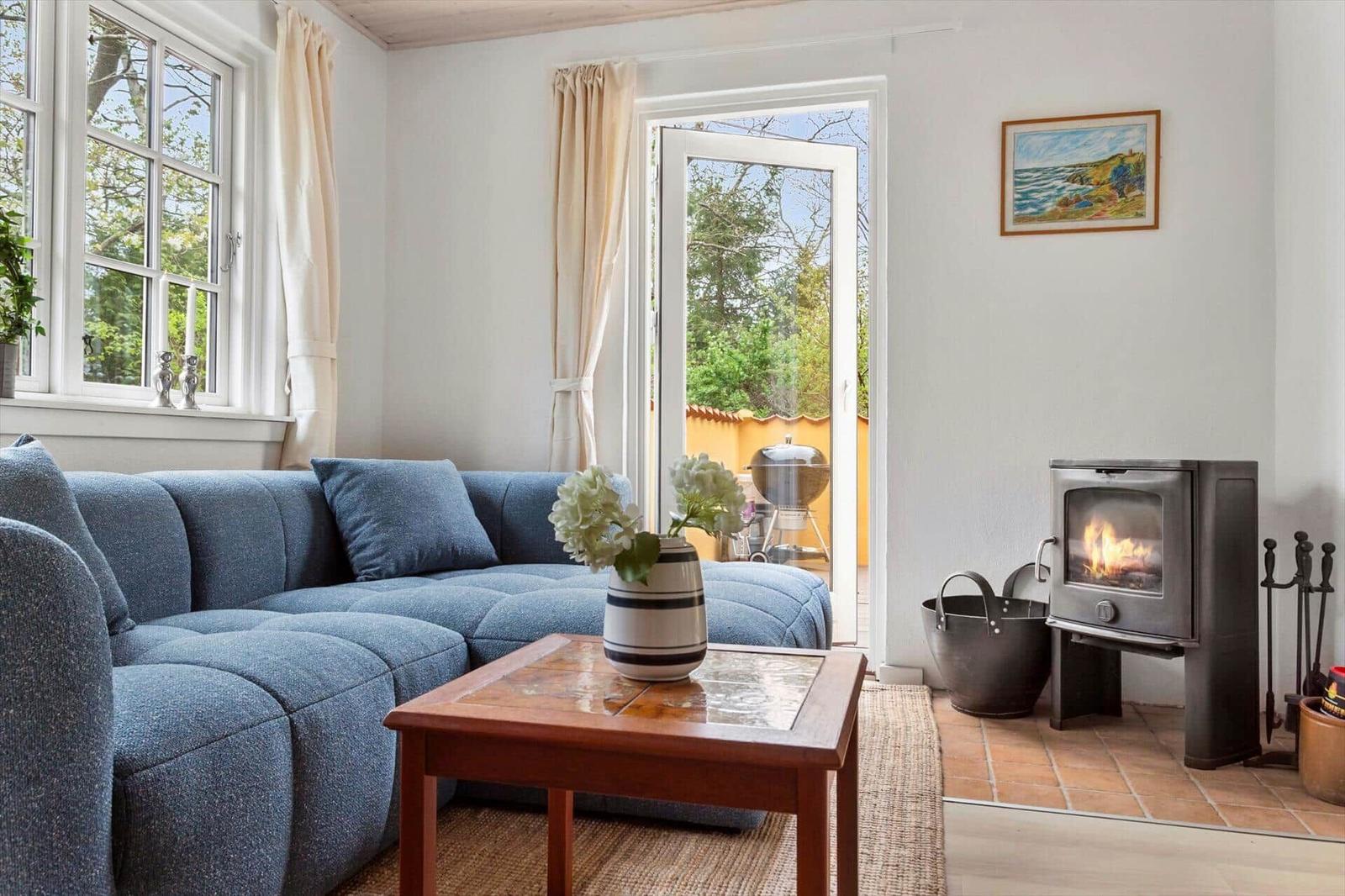 A living room with blue sofa, fireplace, and terrace door.