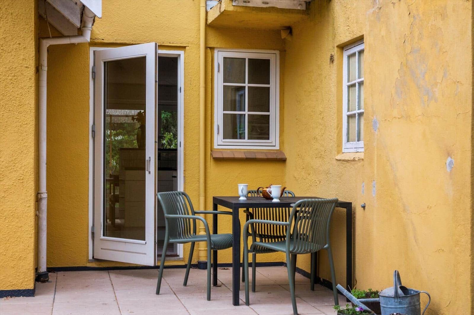 Patio with table, two chairs, and open door to the house.
