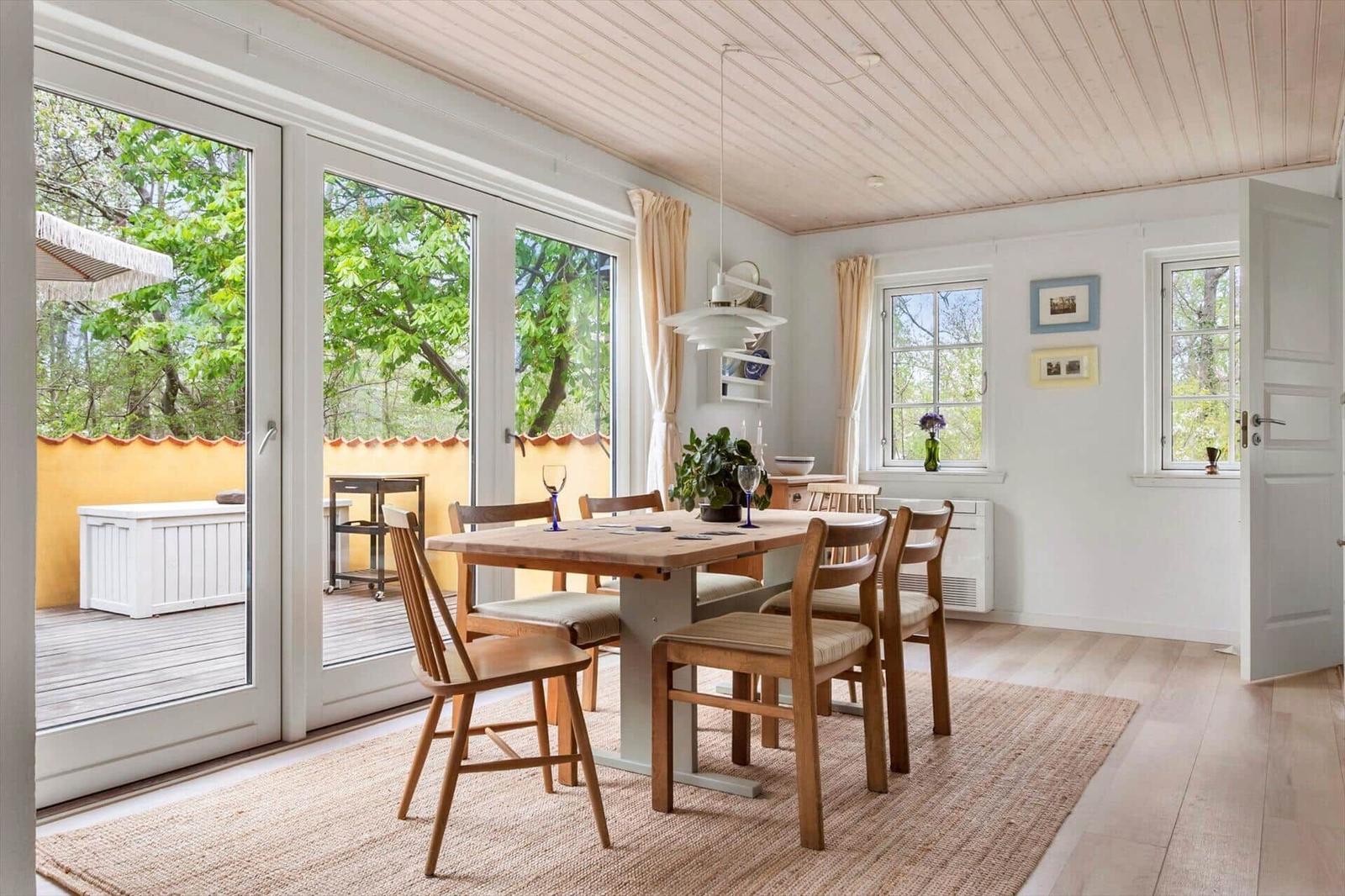 Dining room with wooden table, chairs, and view of terrace.