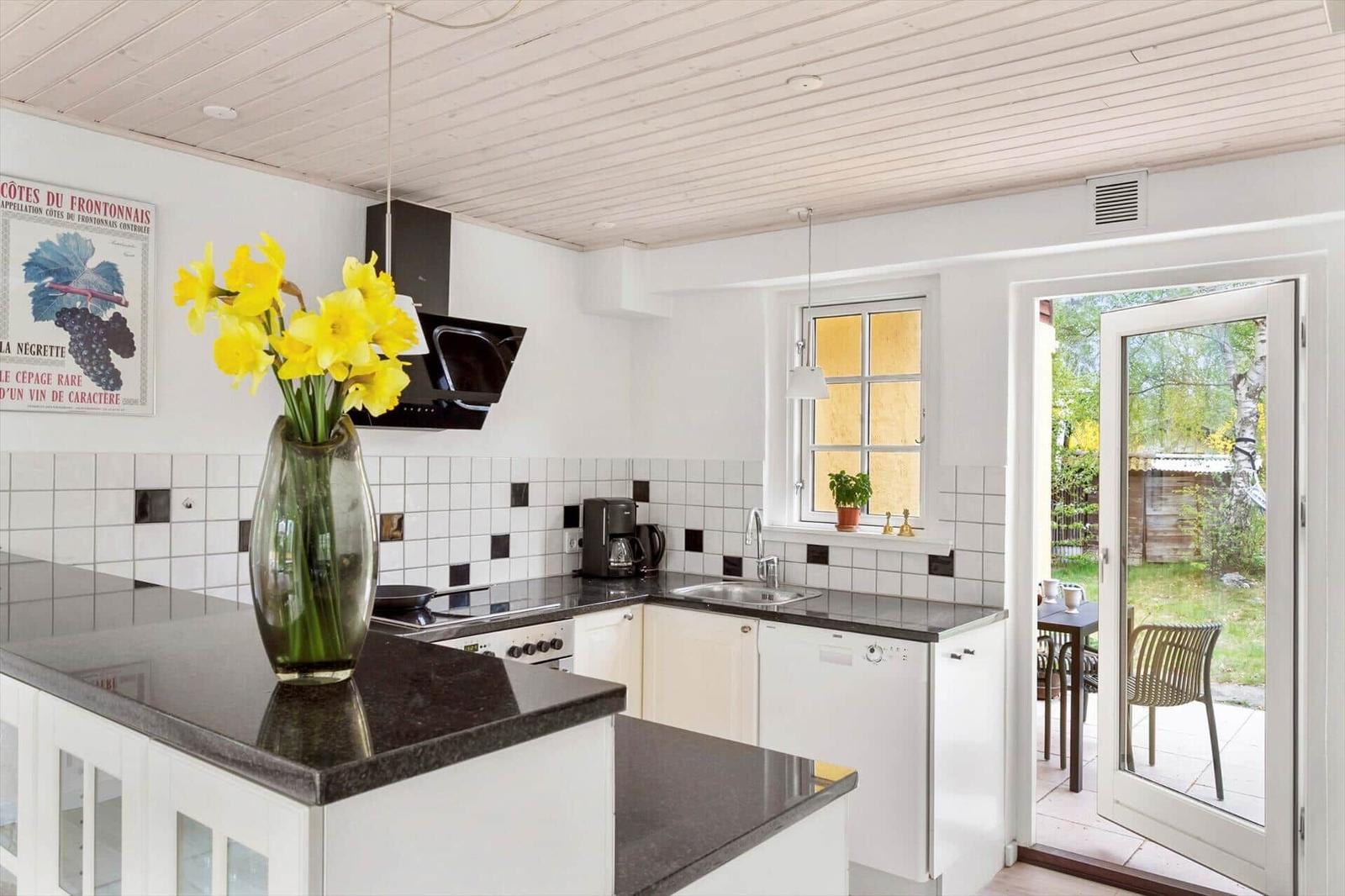 Kitchen with black countertops, white cabinets, and window to the garden.