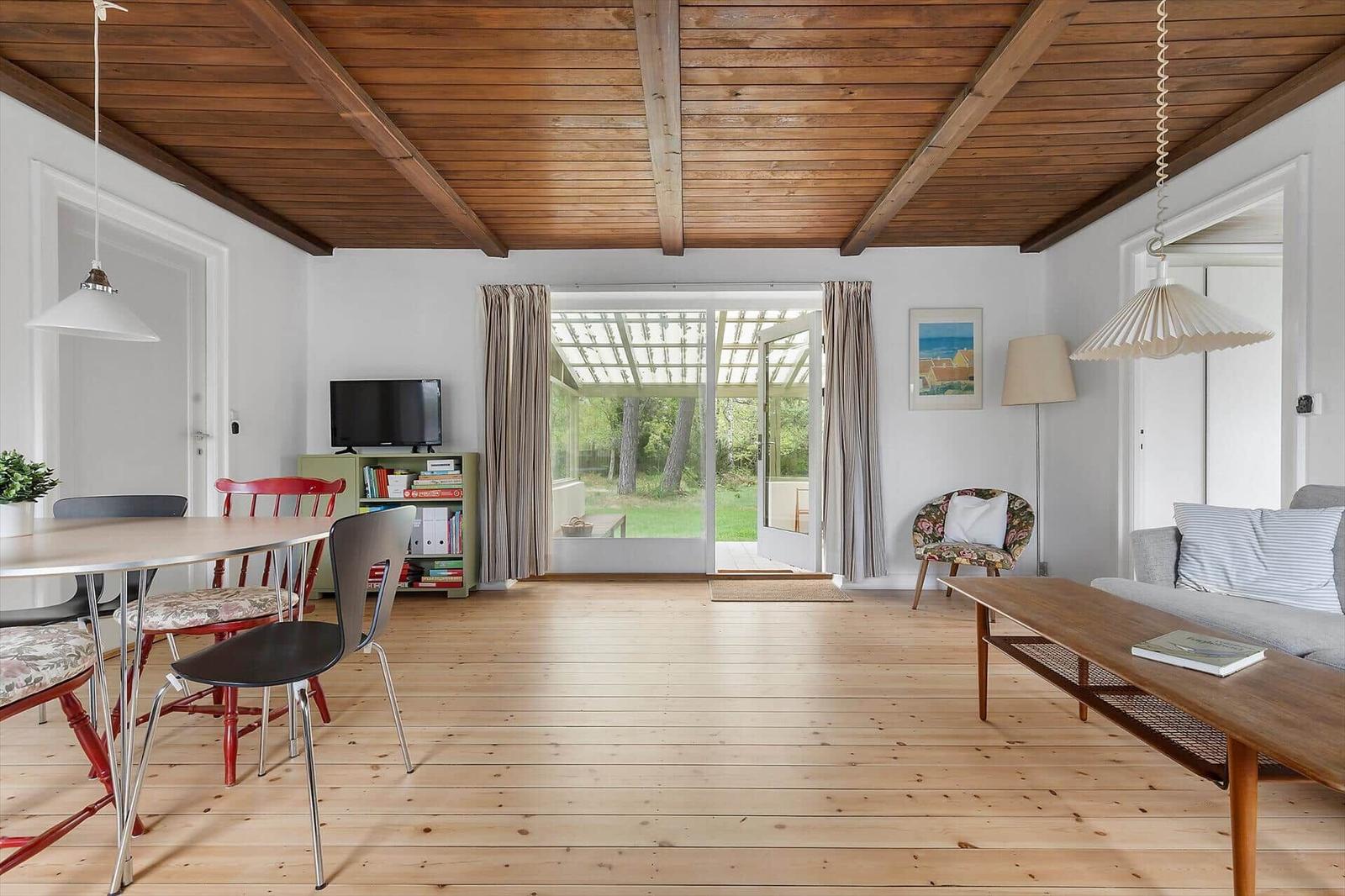 Room with wooden ceiling, dining area, and living area with garden view