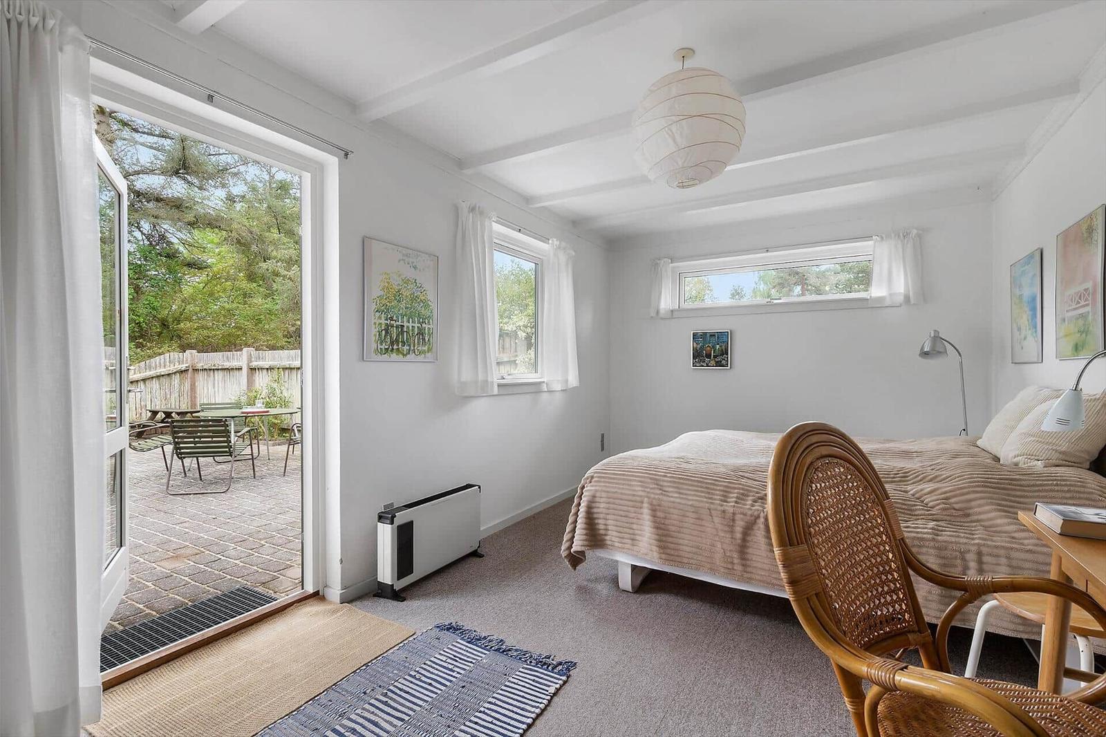 Bedroom with bed, chair, and view of the garden.