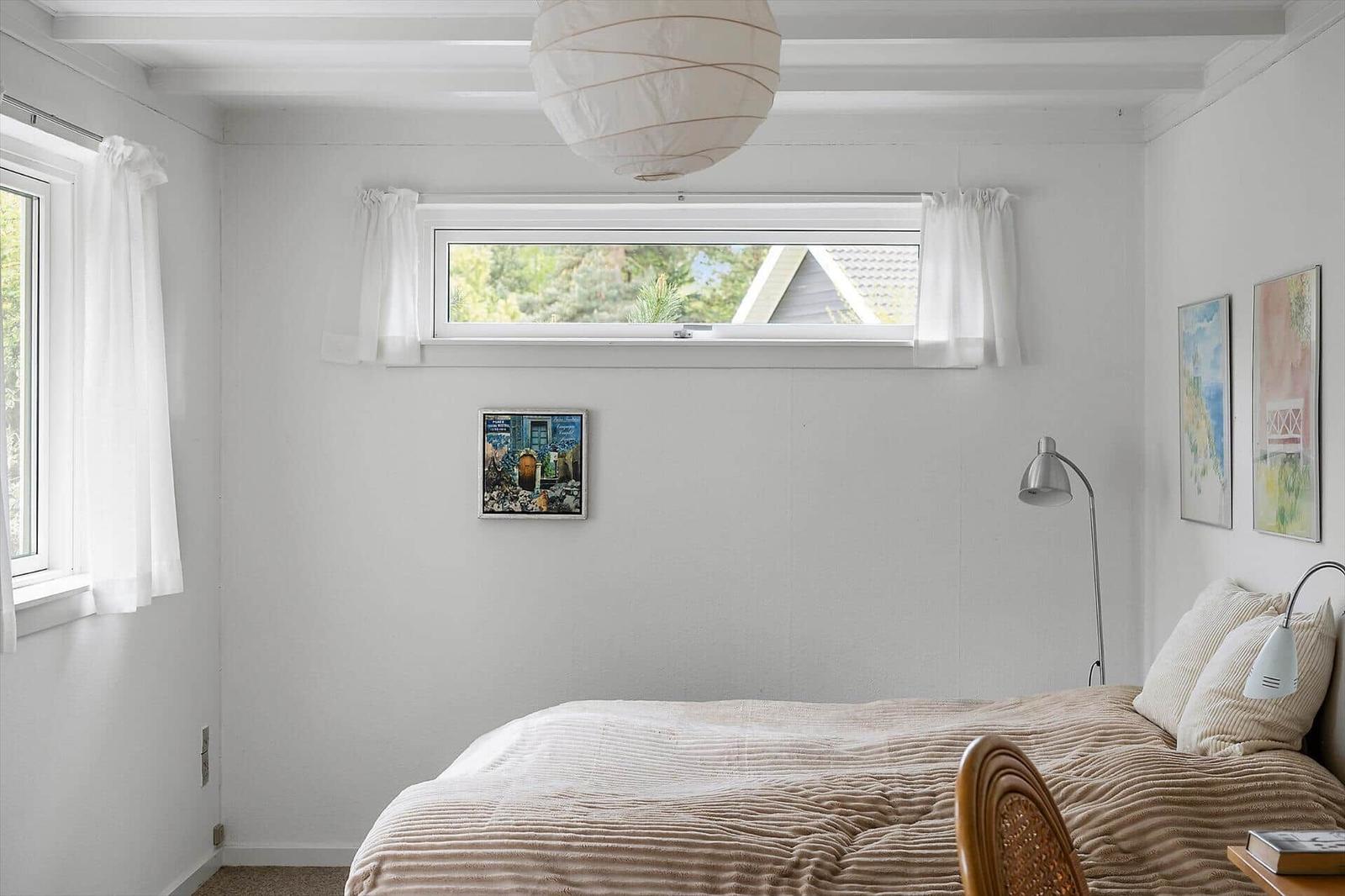 Bedroom with bed, windows, and ceiling lamp.