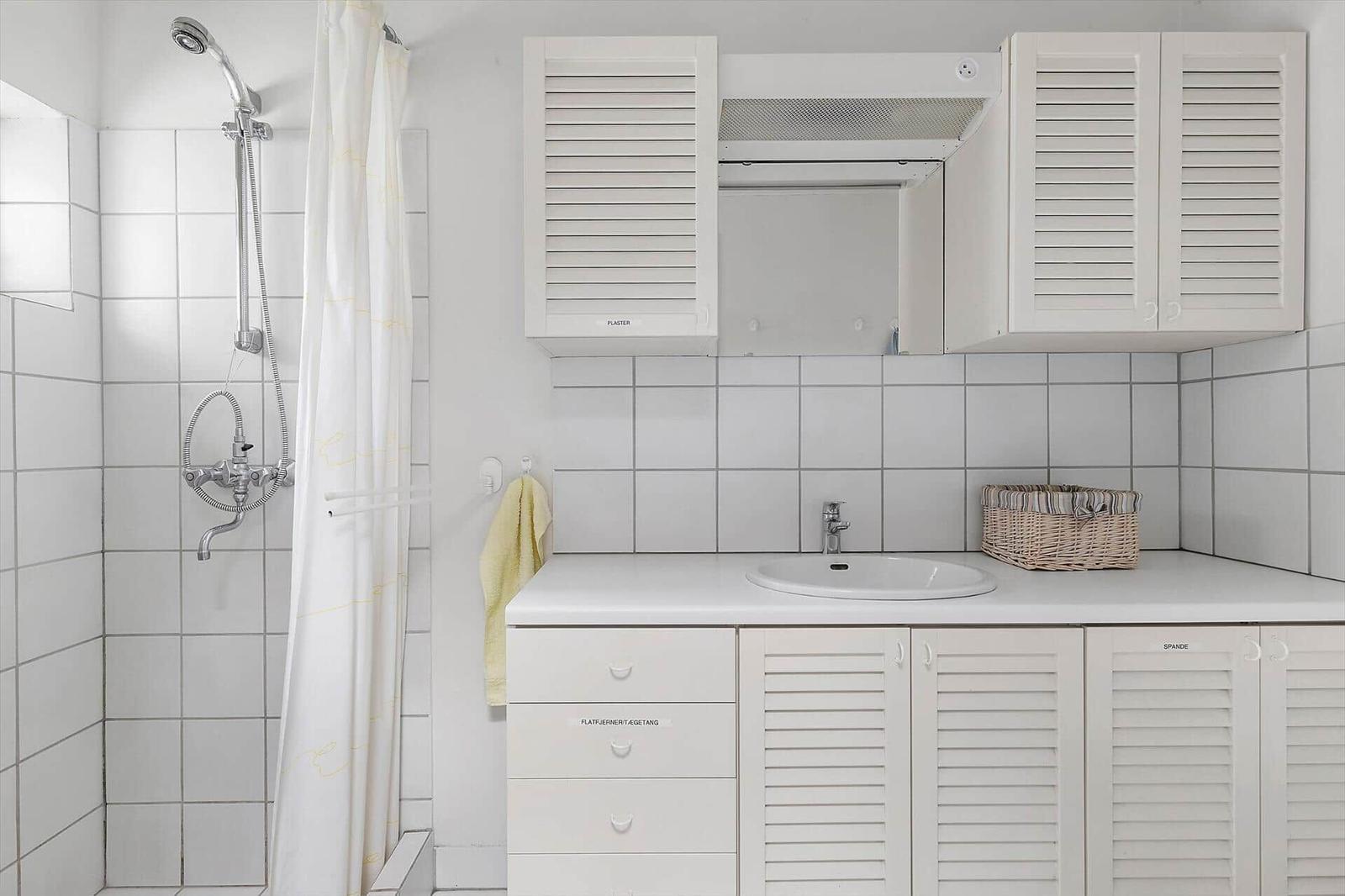 Bathroom with shower, sink, and white cabinets.