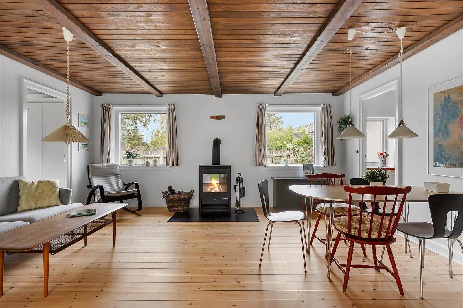 Living and dining area with fireplace, wooden floor, and windows.
