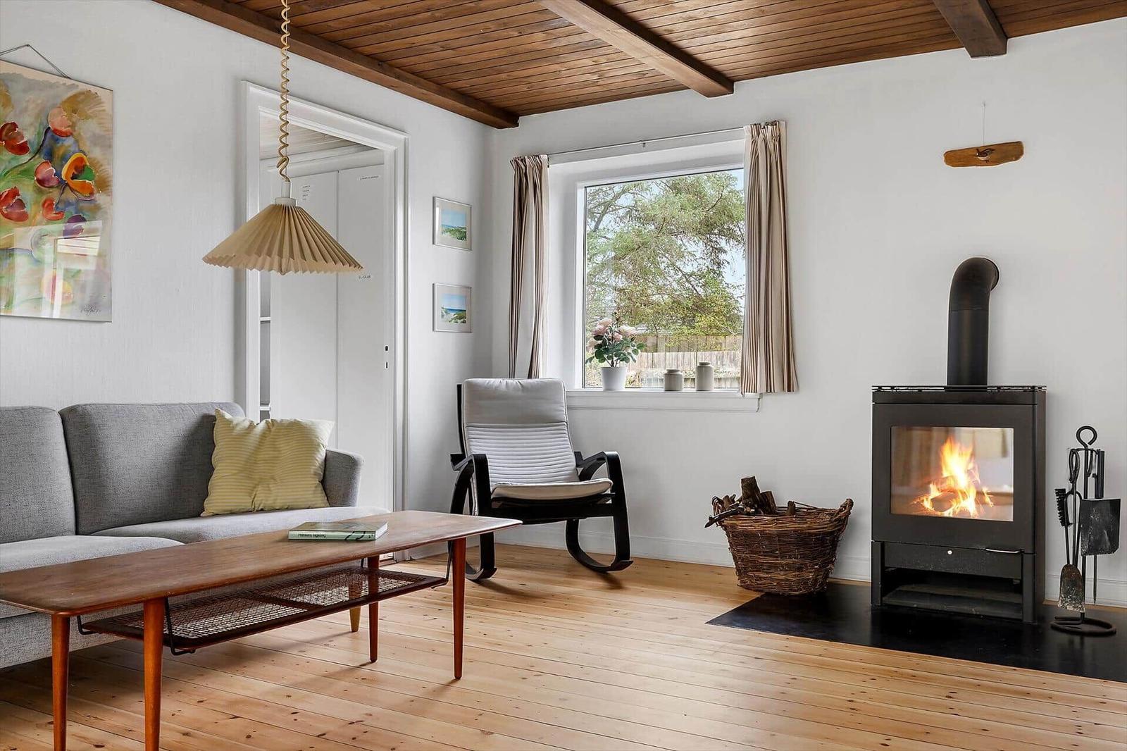 Living room with fireplace, sofa, table, and window view.