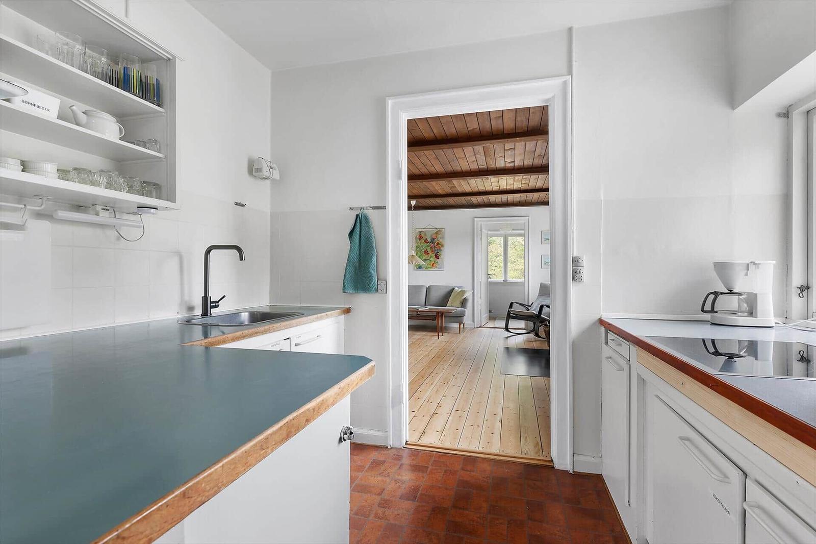 Kitchen with worktop and view into living room with wooden floor and ceiling beams.