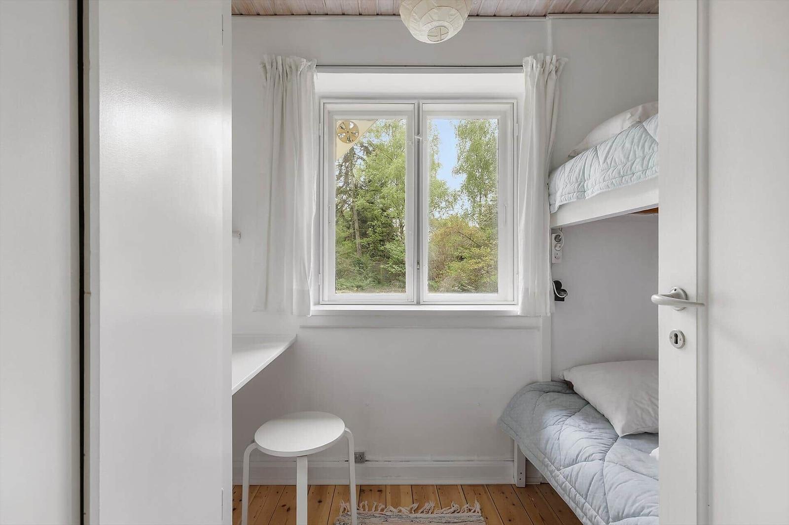 Room with bunk bed, window, and desk.