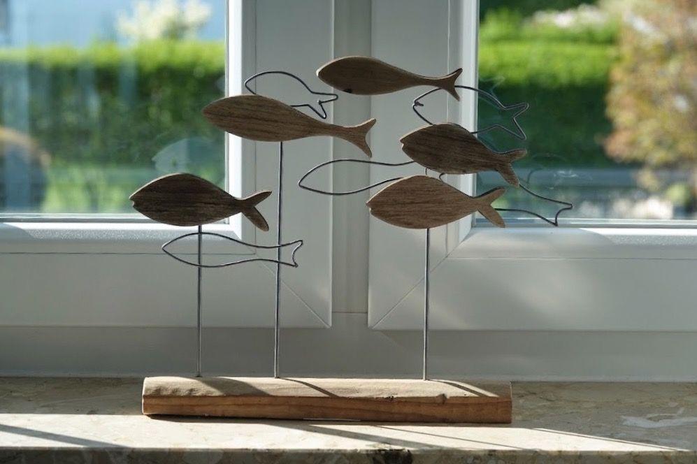 Holz- und Metallfische dekorieren den Fensterbrett.