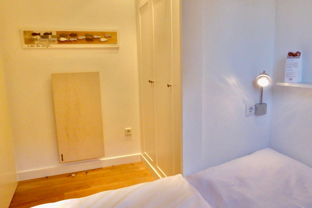 Schlafzimmer mit Bett, Wandlampe und Kleiderschrank.