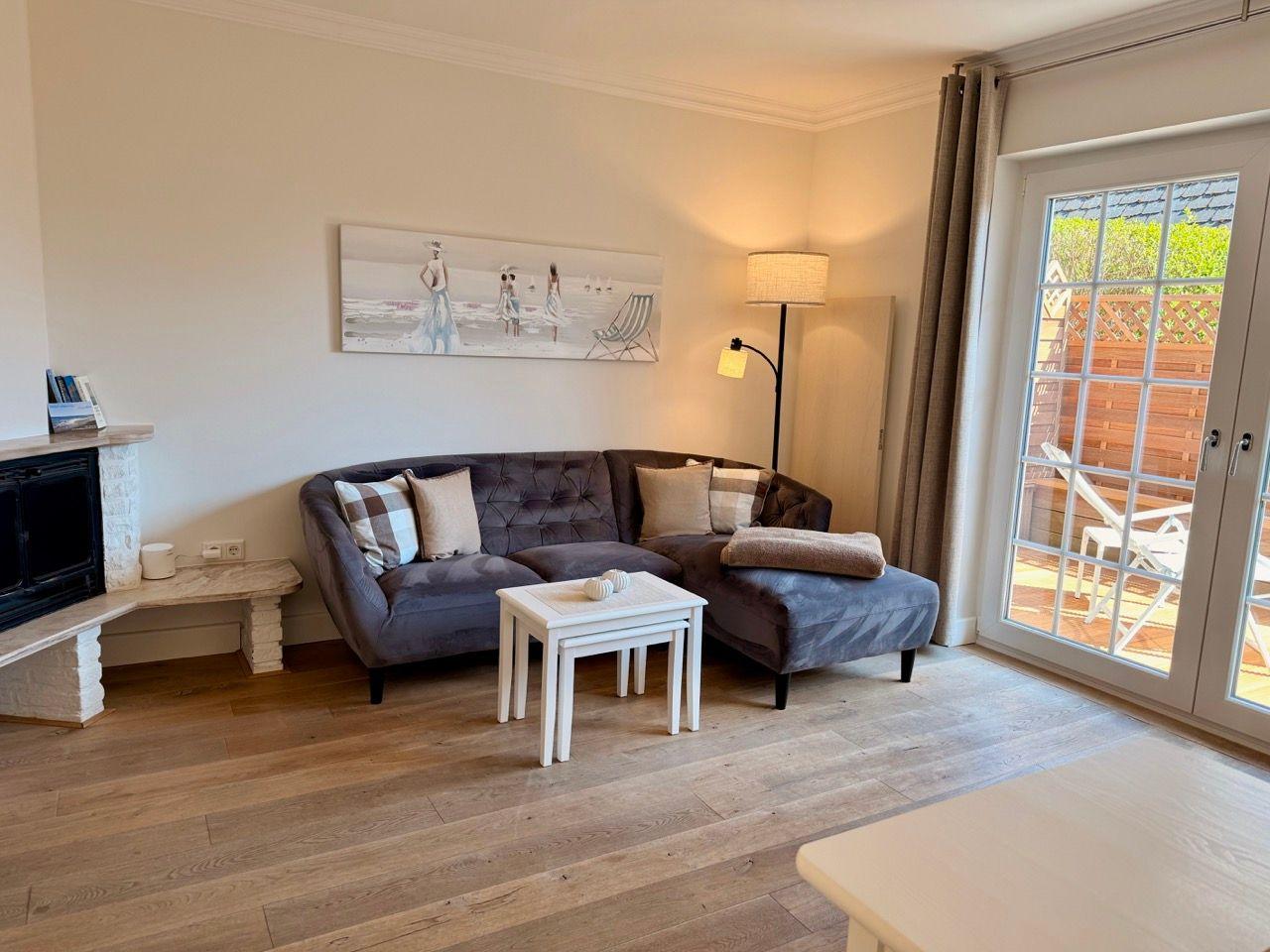 Wohnzimmer mit Sofa, Kamin und Blick auf die Terrasse.