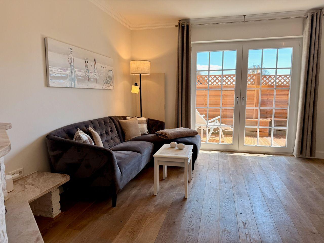 Wohnzimmer mit Sofa, Tisch und Terrassentür. Holzboden und Wandbild.
