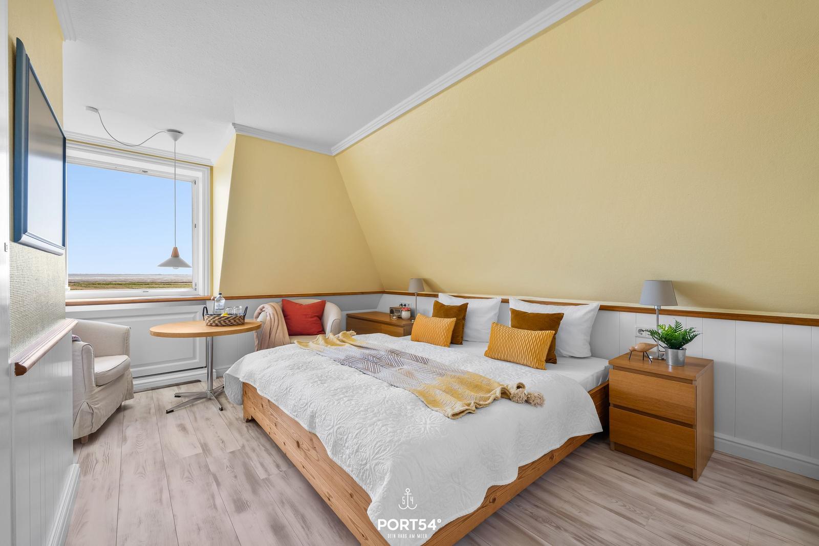 Bedroom with large bed, window view, and wooden furniture.