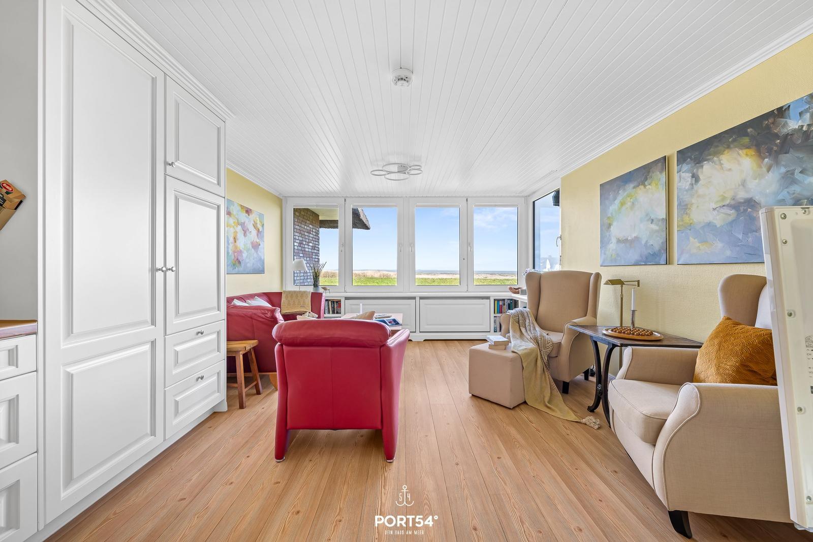 Living room with red armchair, side table, and window view of the landscape.