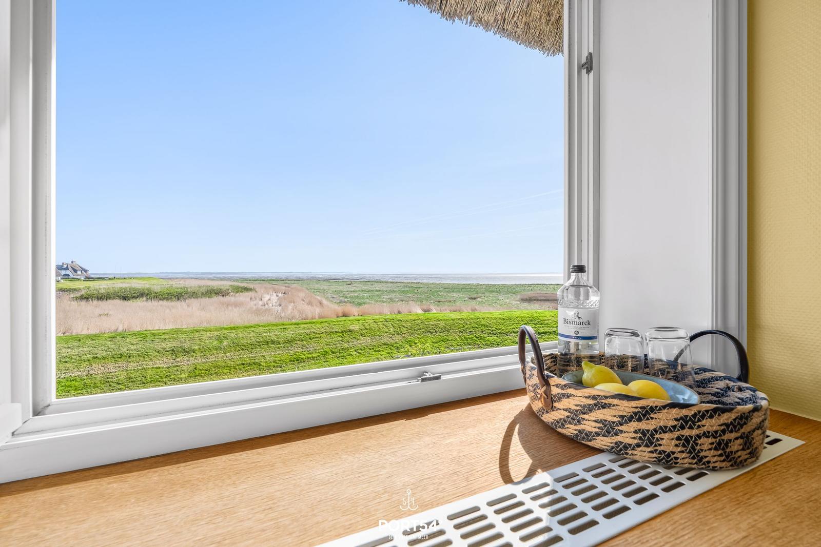 Through the window, you can see a green meadow and the sea.