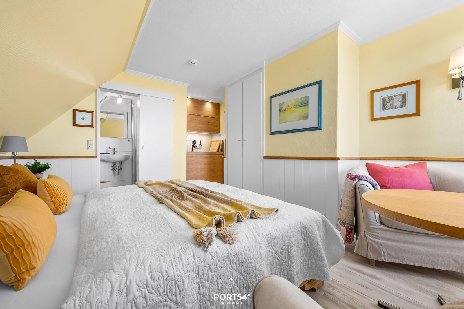 Bedroom with bed, sofa, and view into bathroom and kitchen.