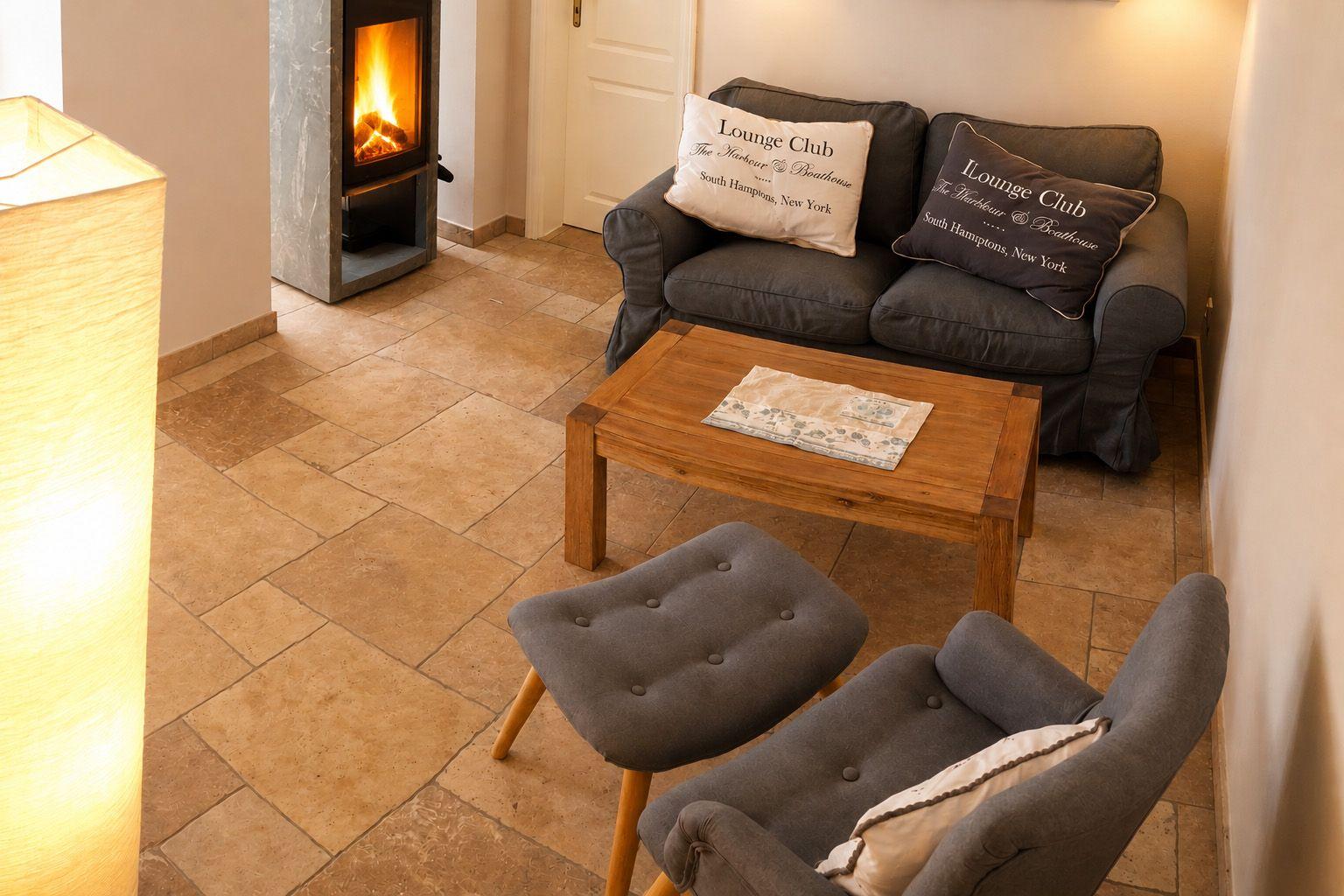 Ein Wohnzimmer mit Sofa, Sessel, Kamin und Holztisch.