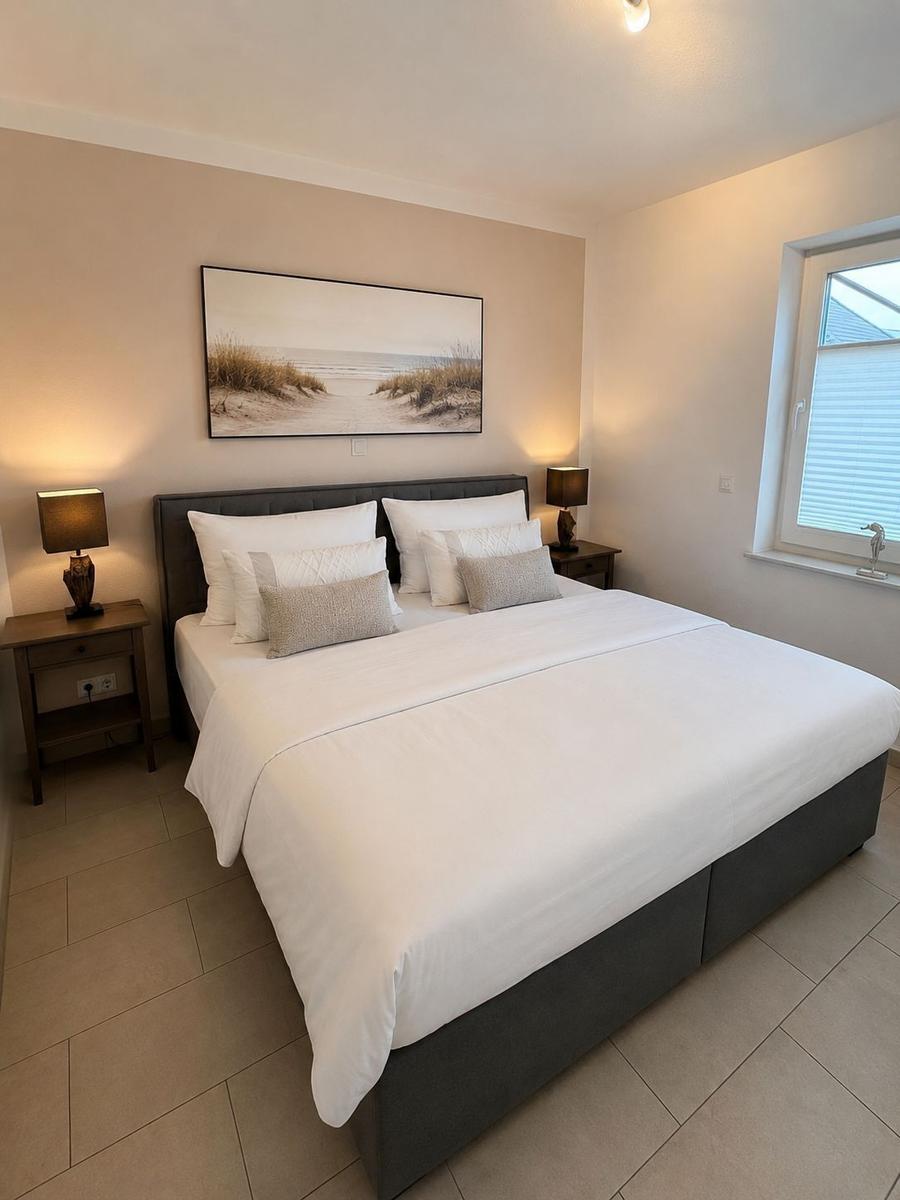 Schlafzimmer mit großem Bett, zwei Nachttischen und Wandbild