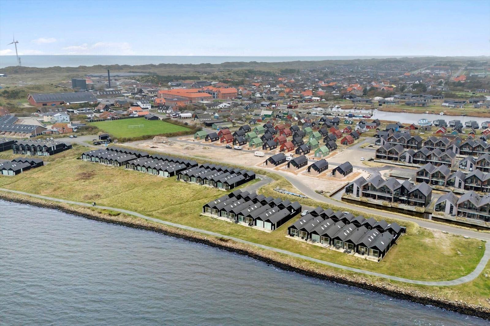 Uferpromenade mit modernen Häusern und Blick auf die Stadt und das Meer.