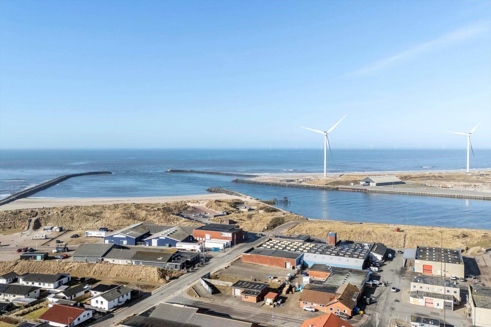 Meer, Windkraftanlagen und Hafenbereich mit Gebäuden und Straßen