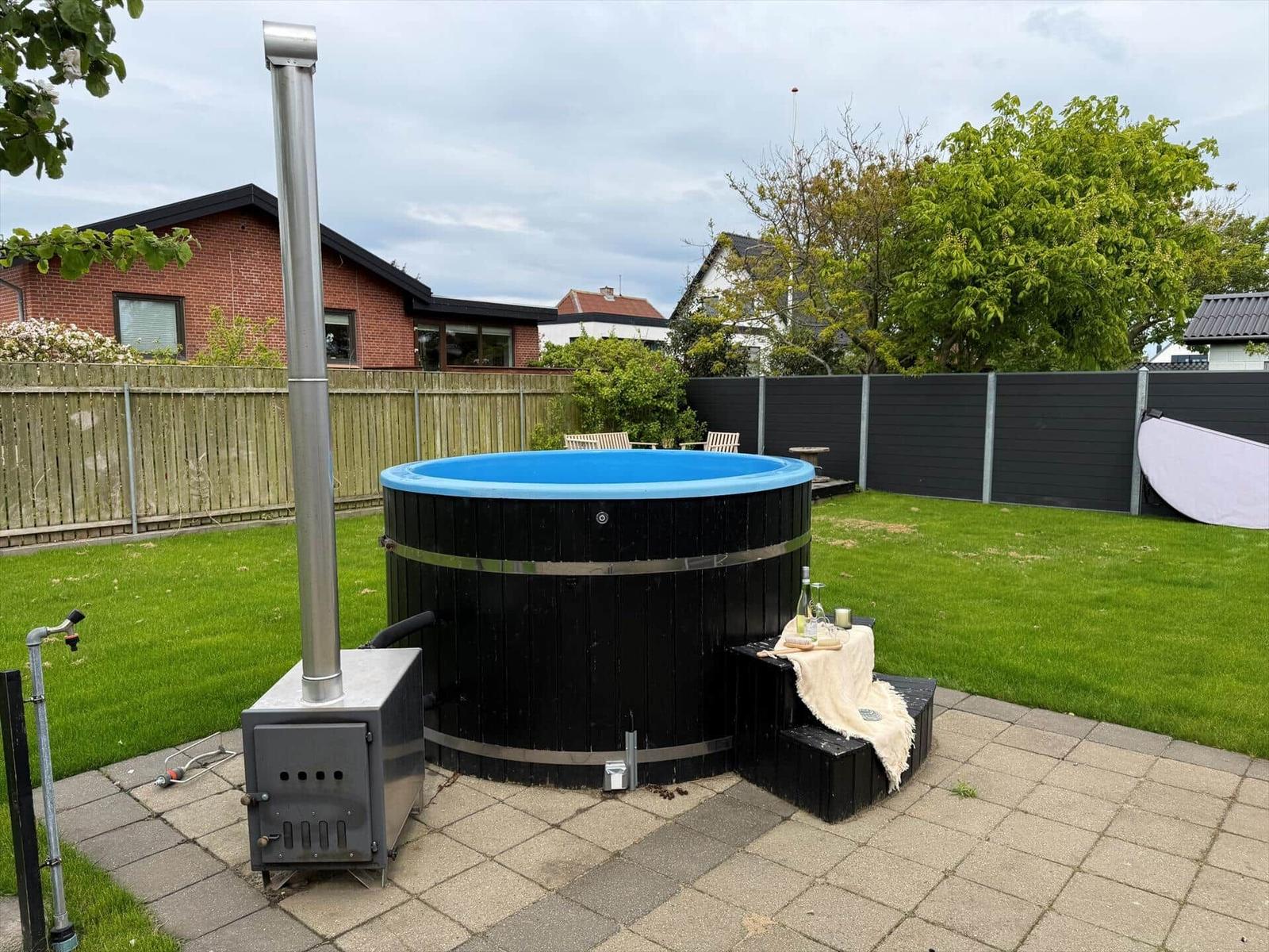 Hochwertiger Whirlpool mit Holzrahmen und Heizung im Garten. Grünfläche und Sitzgelegenheiten.