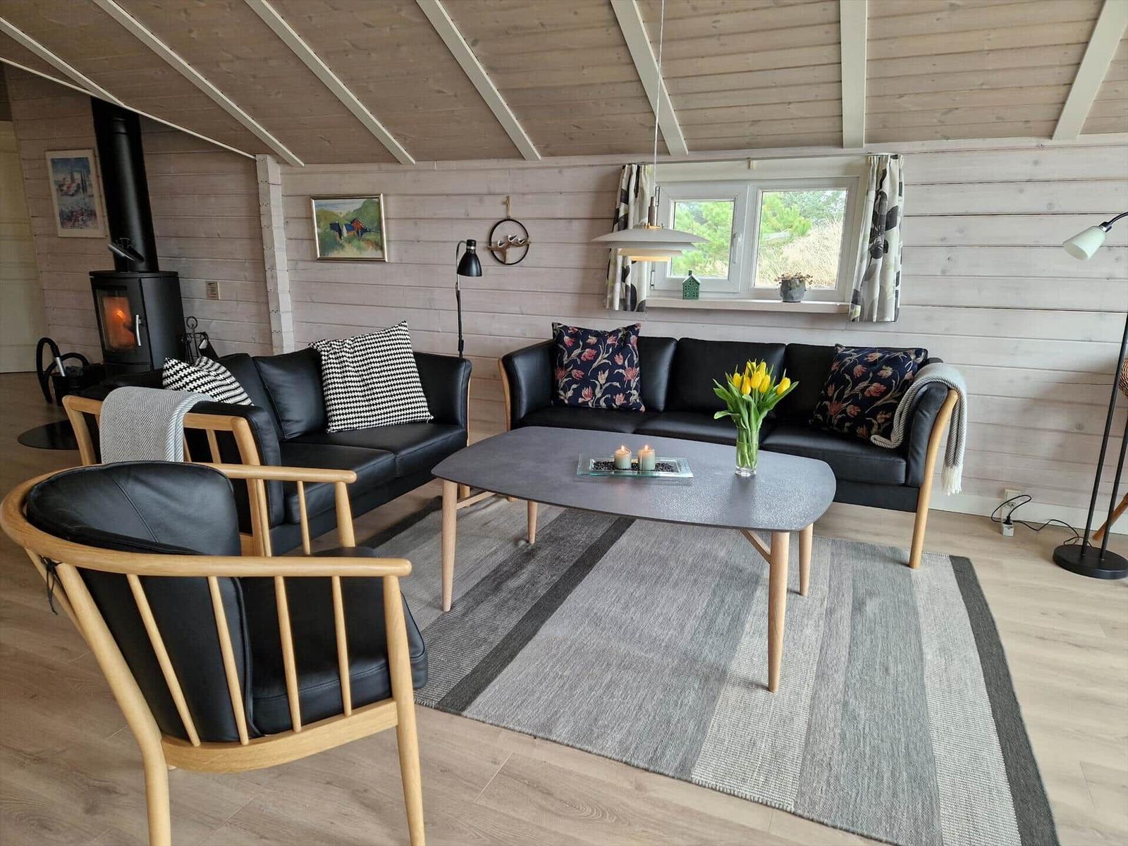 Wohnzimmer mit zwei schwarzen Sofas, Holzstühlen und einem Kamin.