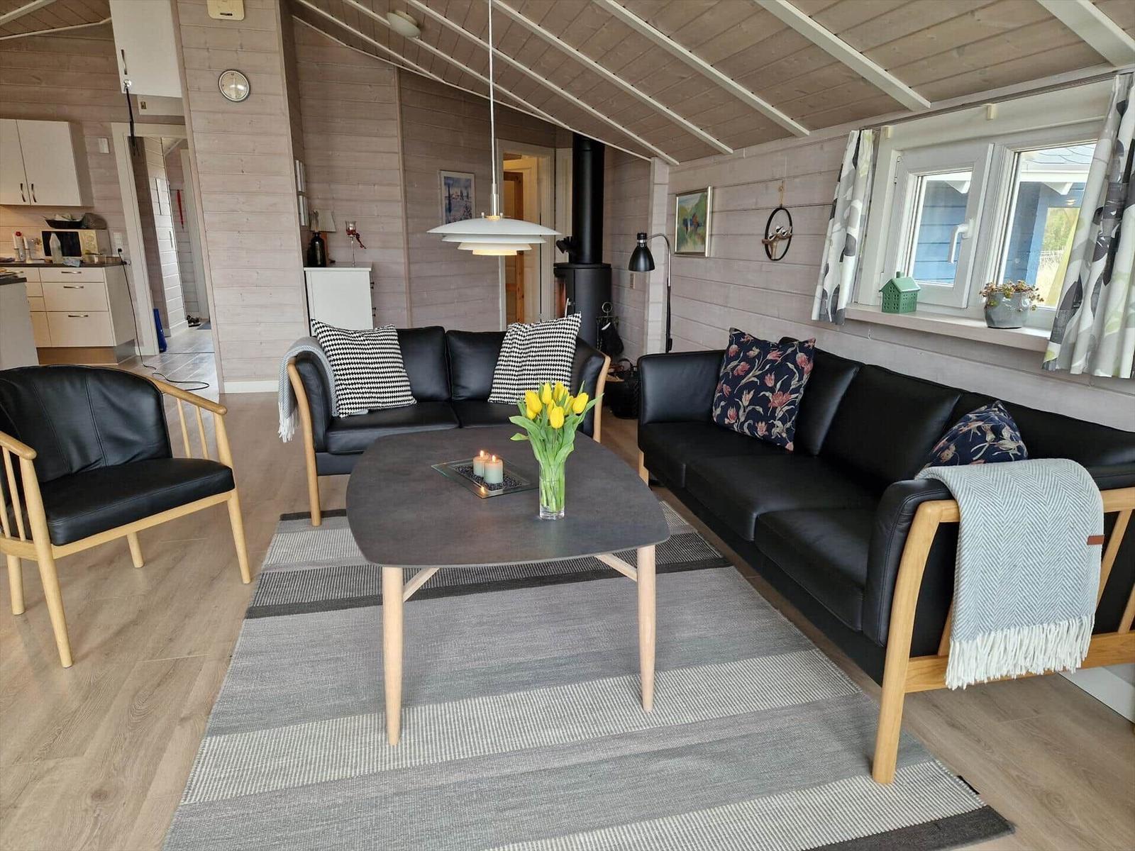 Wohnzimmer mit zwei schwarzen Sofas, Tisch mit Tulpen und Holzfußboden.