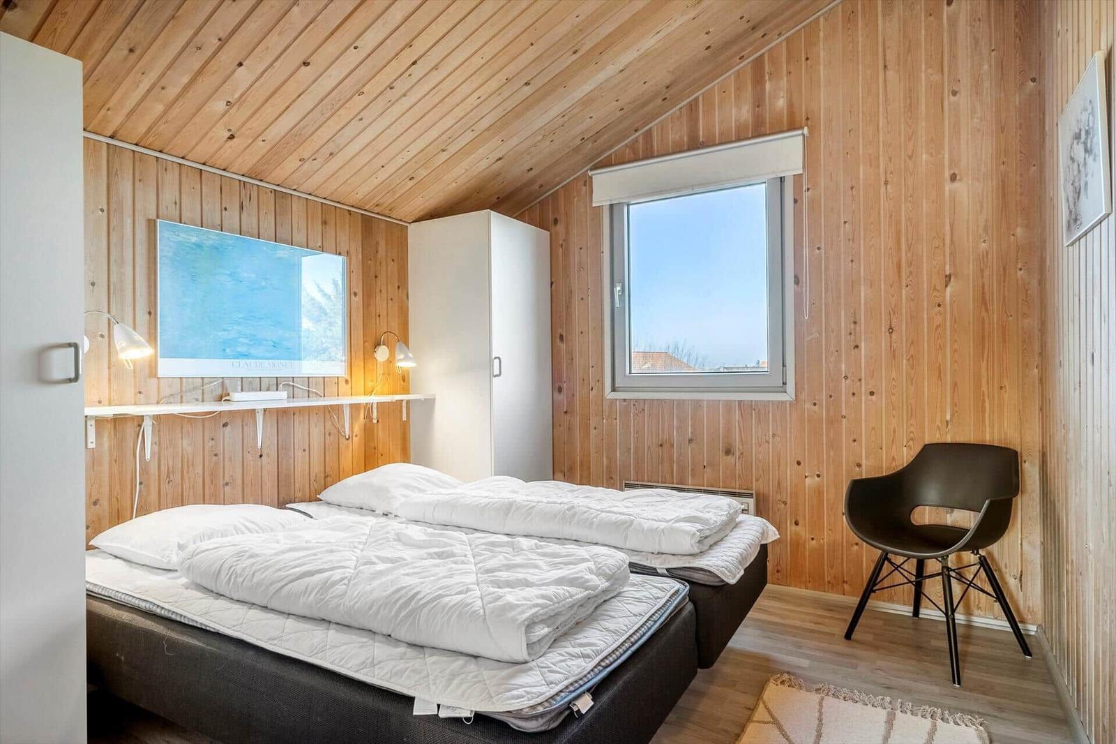 Schlafzimmer mit Holzwand, Bett, Fernseher und Stuhl