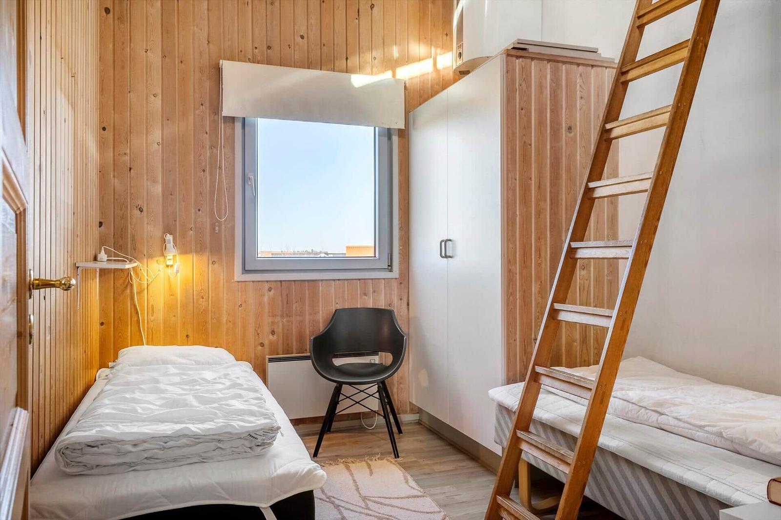 Zimmer mit Doppelbett, Holzwand, Fenster und Leiter zu oberem Bett.