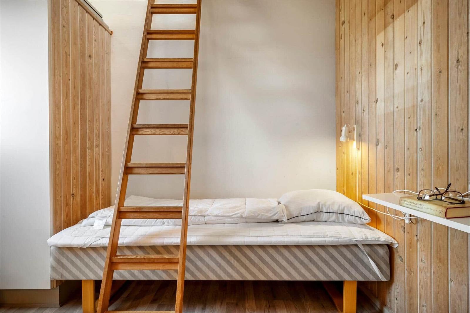 Ein Bett mit Leiter und Holzwand im Schlafzimmer