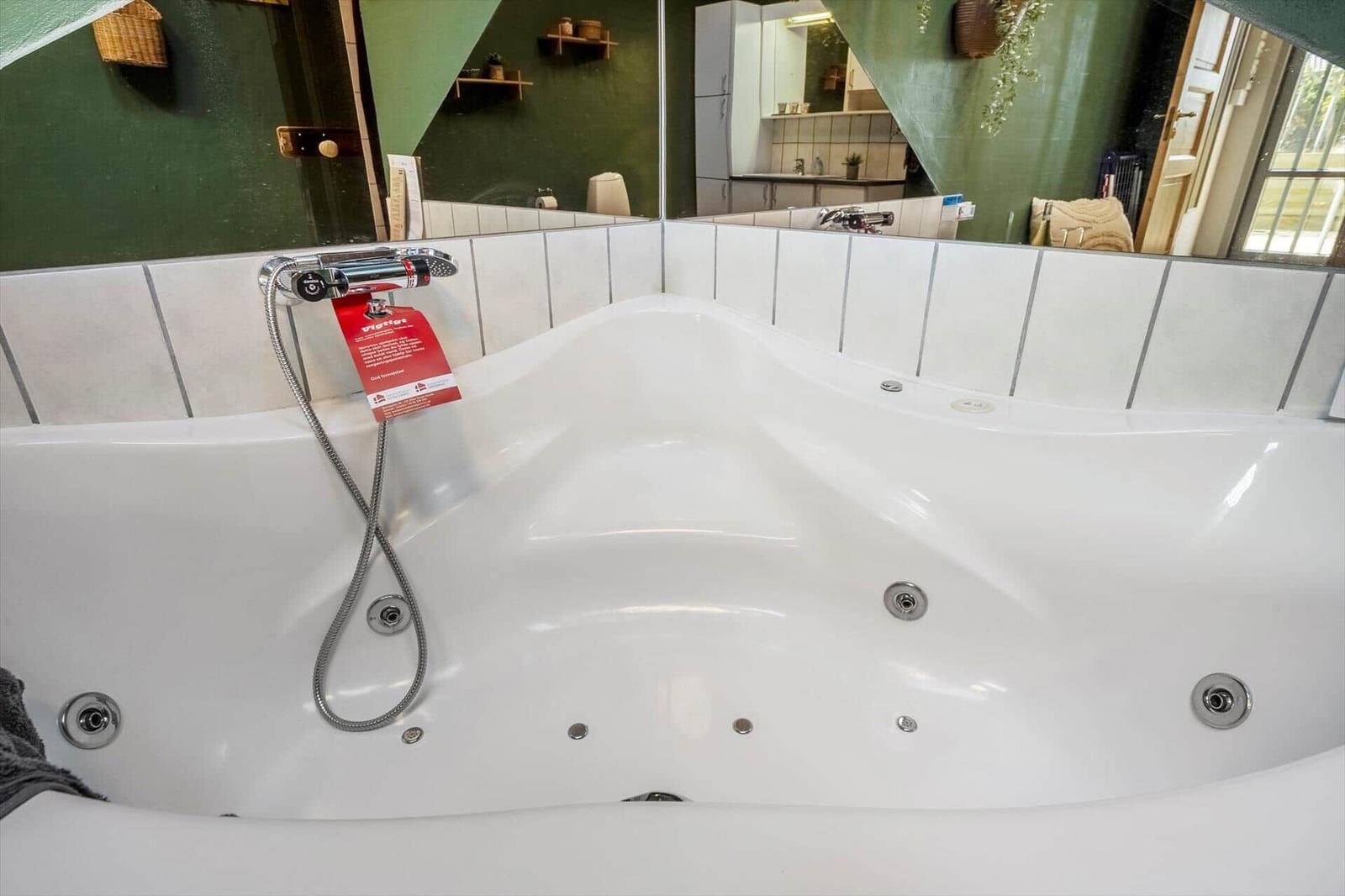 Eine große Whirlpool-Badewanne mit Duschkopf und Armaturen.