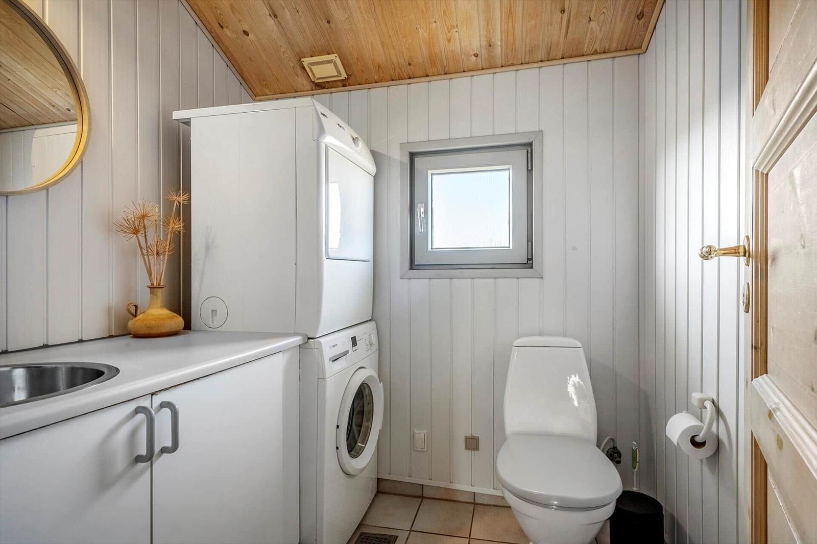Badezimmer mit Waschmaschine, Trockner, Toilette und Fenster