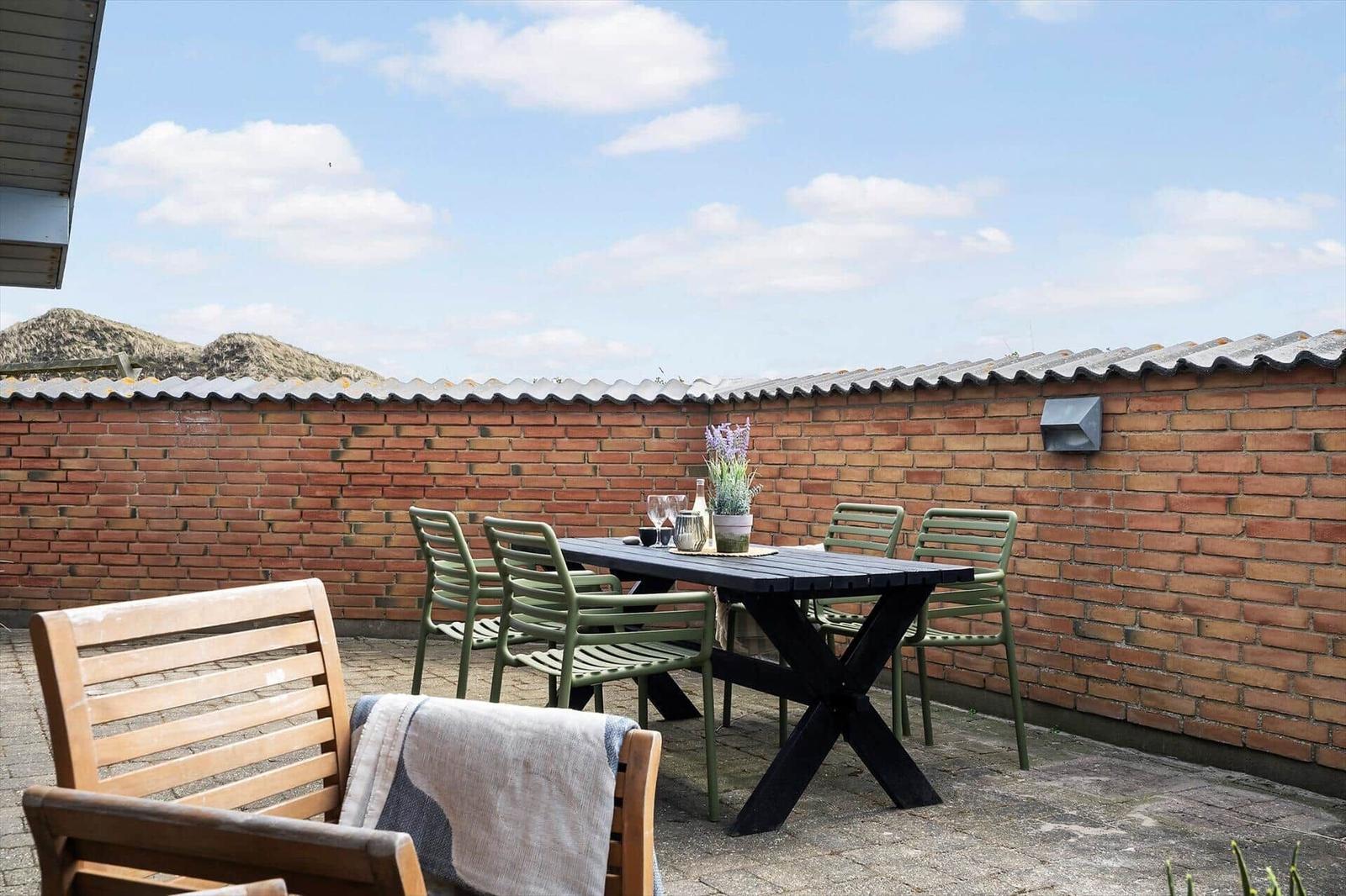 Terrasse mit Tisch, Stühlen und Blick auf Berge.